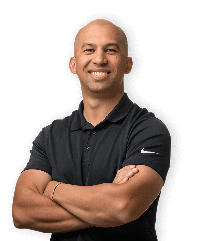 A smiling man with a shaved head wearing a black Nike polo shirt stands with his arms crossed against a plain black background.